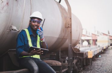 tecnico-de-engenharia-de-maquinas-africano-usando-um-capacete-bosques-e-colete-de-seguranca-para-consertar-o-trem-com-o-uso-de-tablet_73622-2496